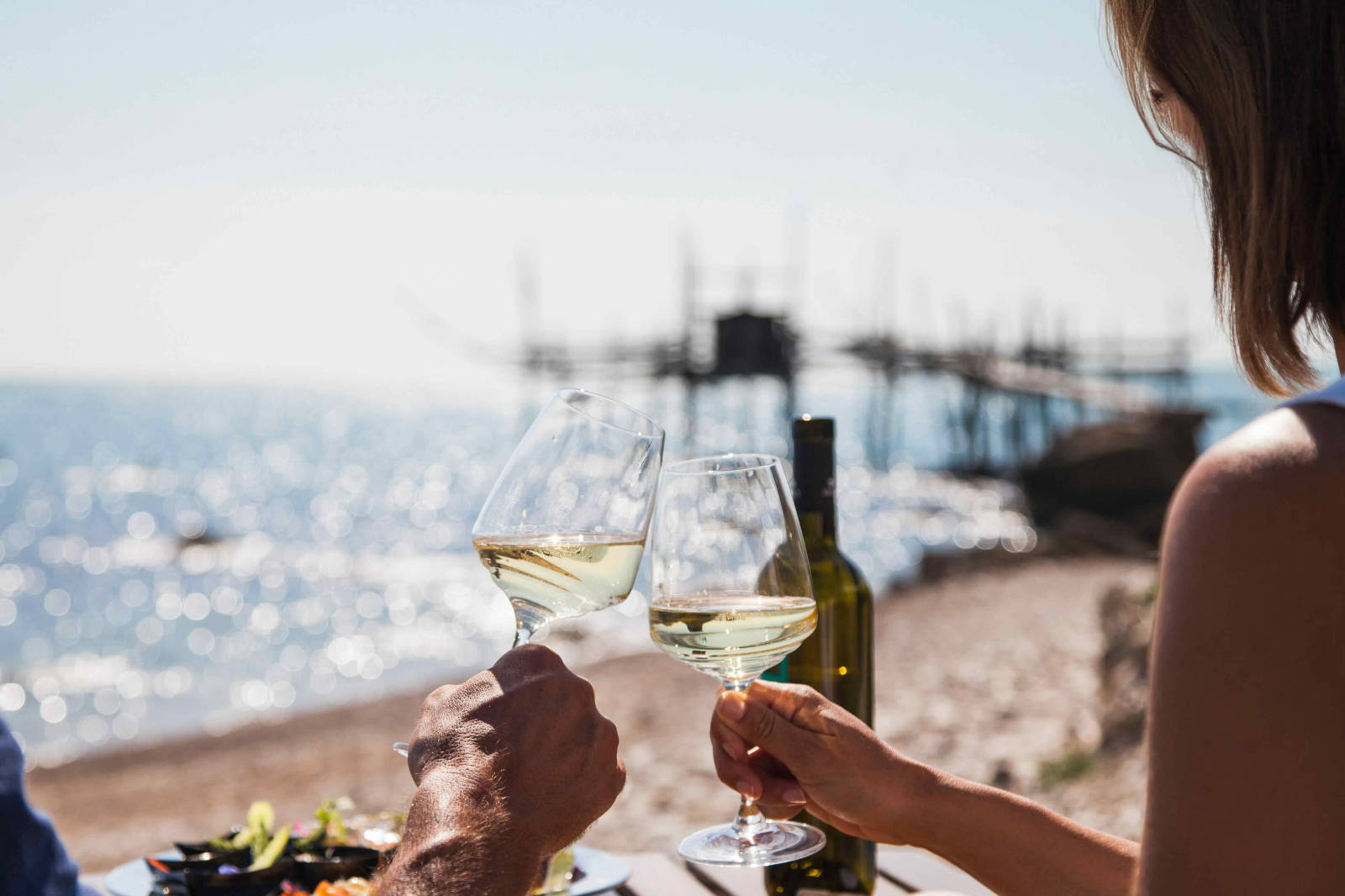 Brindisi con vino bianco davanti a un trabocco della Costa dei Trabocchi