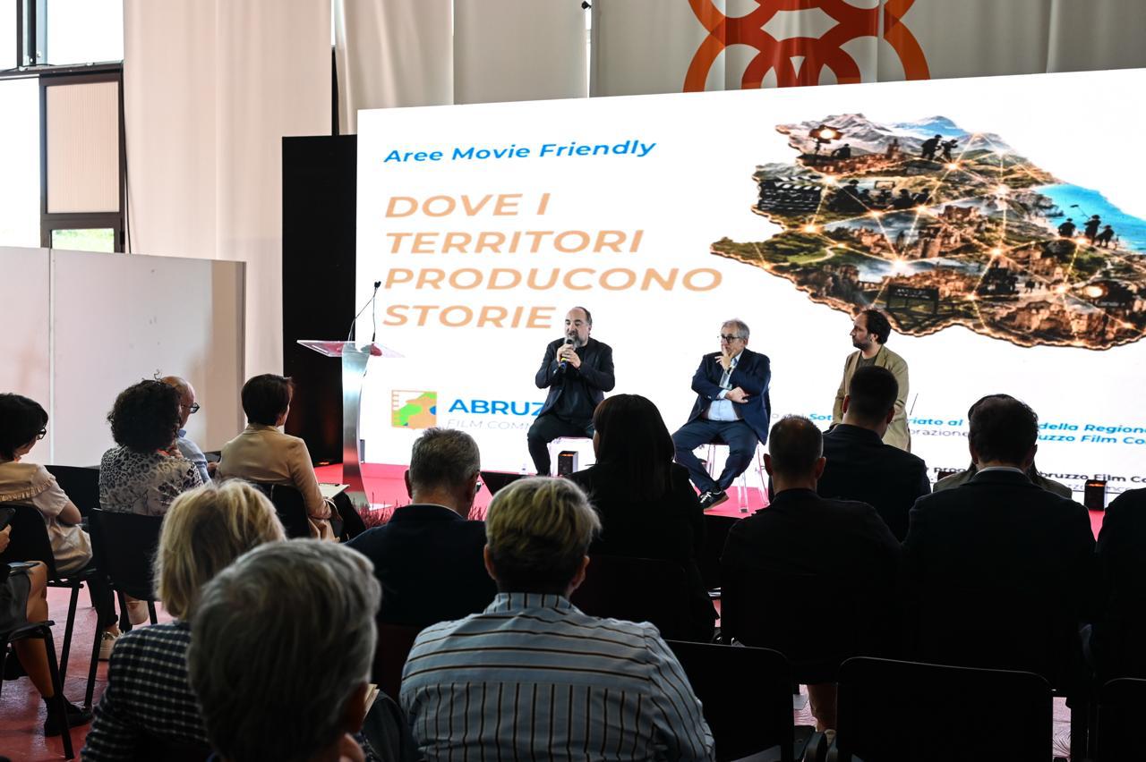 La presentazione di Aree Movie Friendly a Piacere, Abruzzo!: i relatori sul palco davanti allo schermo “Dove i territori producono storie” e il pubblico in sala